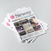 A stack of printed magazines or brochures fanned out on a light gray studio background. The top magazine is angled to show its front cover, with the title 'Newsy' prominently visible and several smaller article photos and text blocks on the cover.