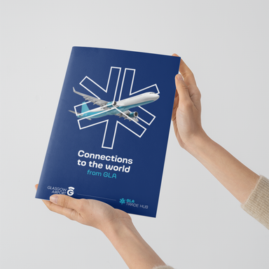 A person holds a printed airline brochure.