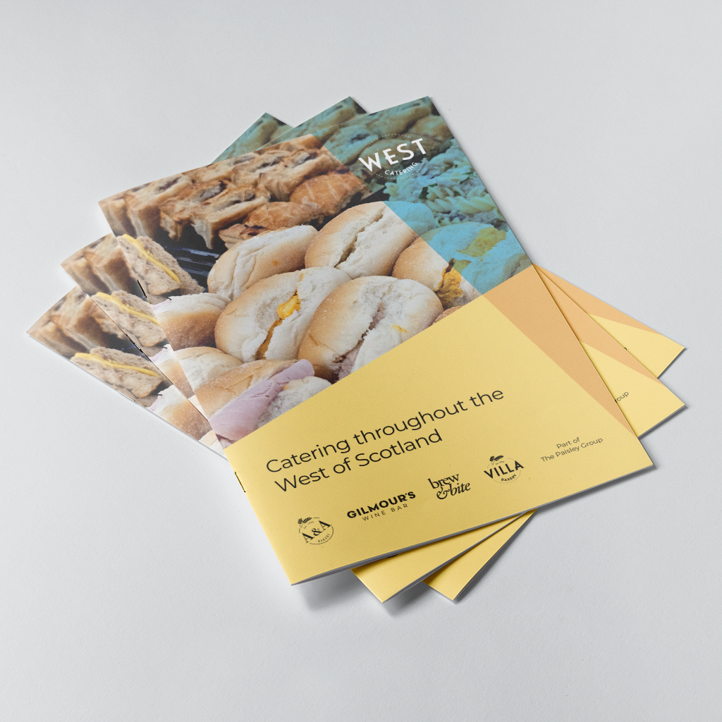 A stack of printed catering brochures on a light grey background. 