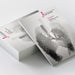 A stack of printed Pefect Bound Brochures on a light grey studio background, with one brochure standing upright to show the cover. The cover has a monochrome artistic illustration and visible text including 'Scopio Society for Art History' and 'Art and Science.